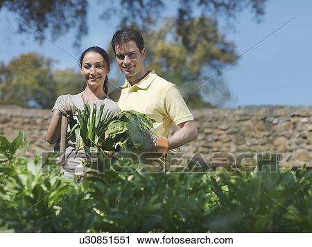 Stock Image - Man and woman with freshly picked vegs. Fotosearch