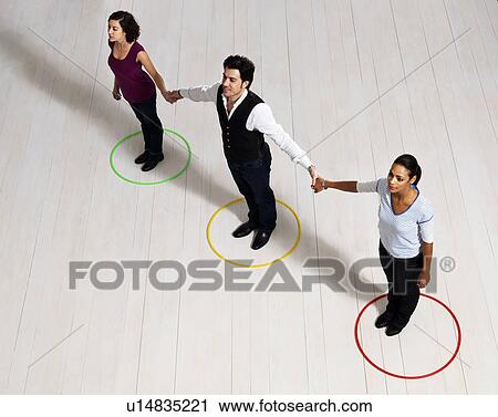 Stock Image - Man and women holding hands in circles. Fotosearch