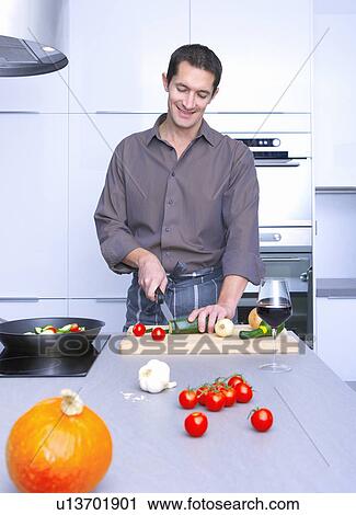 Stock Image - man cooking in a kitchen, and smiling. Fotosearch