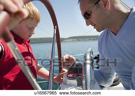 Stock Photography - Man explaining boy compass on yacht. Fotosearch