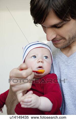 Stock Photography - Man feeding baby. Fotosearch