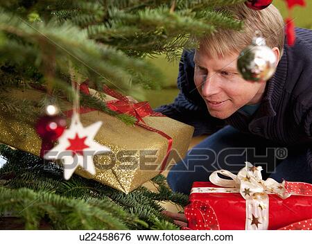 man hiding presents under christmas tree View Large Photo Image Stock Photograph - man hiding presents under christmas tree. Fotosearch