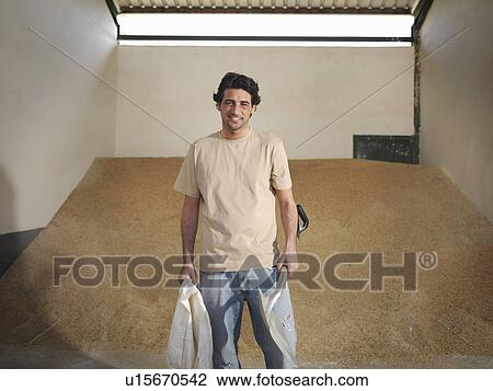 Stock Image - Man holding a spade and bag for feed. Fotosearch