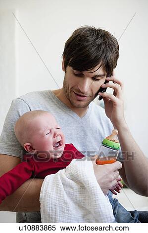 Man holding baby while phoning View Large Photo Image Stock Photography - Man holding baby while phoning. Fotosearch