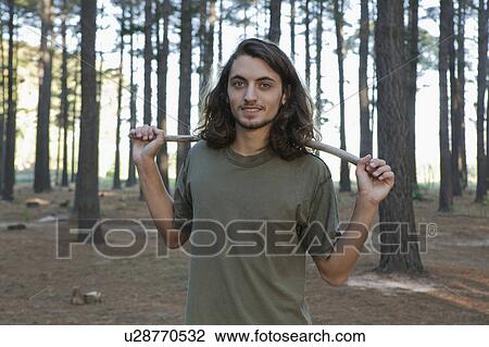 Stock Image - Man holding stick in forest. Fotosearch