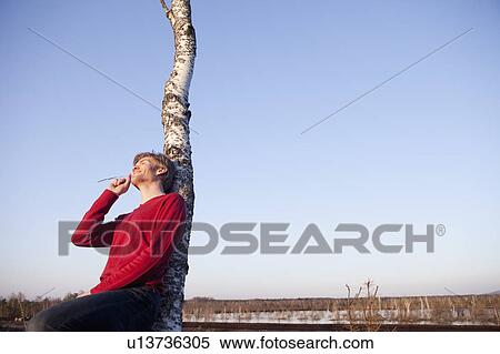 Stock Photography - Man leaning back on tree. Fotosearch