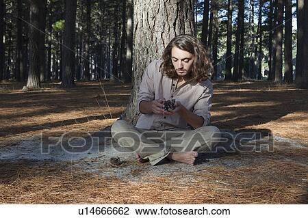 Stock Image - Man looking at pine cone. Fotosearch