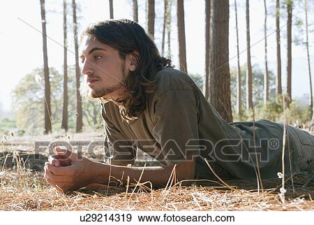 Man looking at plant on forest floor View Large Photo Image Stock Photo - Man looking at plant on forest floor. Fotosearch