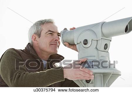 Picture - Man looking through a telescope. Fotosearch