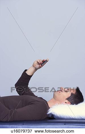 Stock Photo - man lying checking his phone . Fotosearch