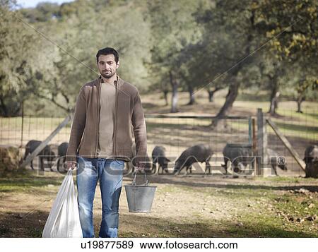 Man on farm holding bucket and bag View Large Photo Image Stock Photo - Man on farm holding bucket and bag. Fotosearch