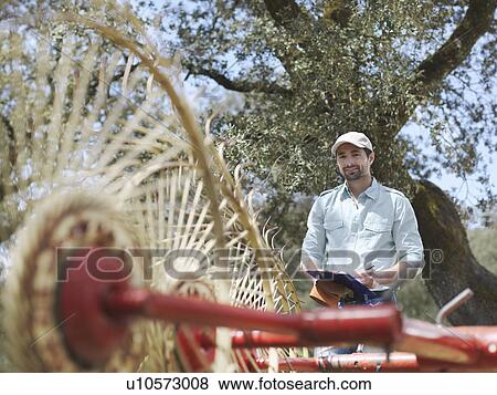 Man on farm with clipboard and hay rake View Large Photo Image Stock Photo - Man on farm with clipboard and hay rake. Fotosearch