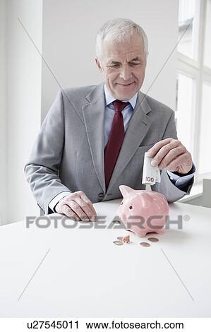 Man putting banknote into piggy bank View Large Photo Image Stock Image - Man putting banknote into piggy bank. Fotosearch