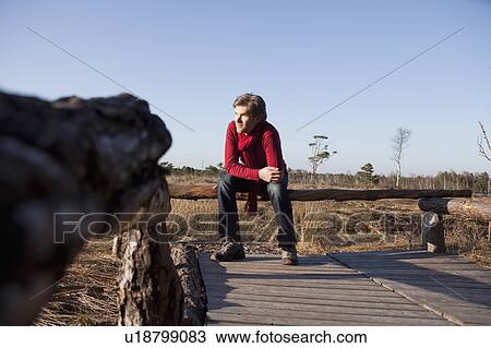 Stock Image - Man relaxing on wooden bench. Fotosearch