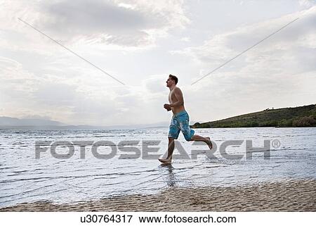 Stock Photo - Man running at beach. Fotosearch