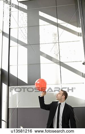 Stock Photograph - Man setting balloon free in office. Fotosearch