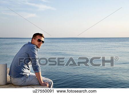Man sitting by sea View Large Photo Image Stock Image - Man sitting by sea. Fotosearch