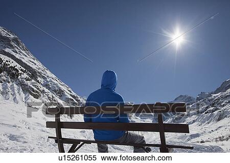 Stock Photography - Man sitting in front of a glacier. Fotosearch