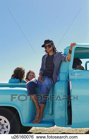 Stock Photograph - Man sitting on side of pickup truck. Fotosearch