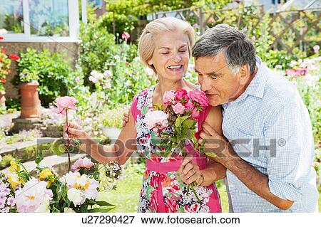 Stock Photo - man smelling flowers in woman's hand.. Fotosearch