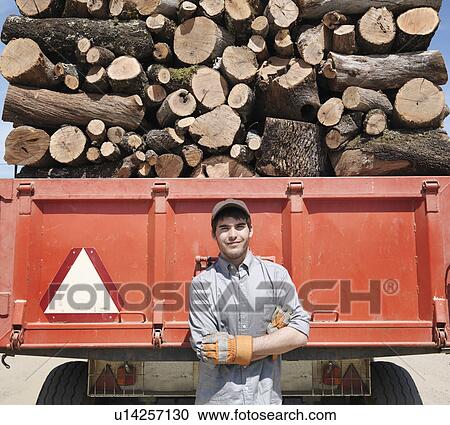 Stock Image - Man standing in front of lorry with logs. Fotosearch