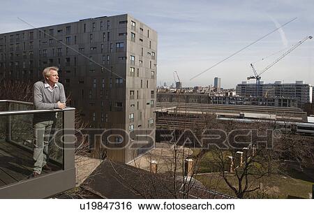 Man standing on balcony View Large Photo Image Stock Photograph - Man standing on balcony. Fotosearch
