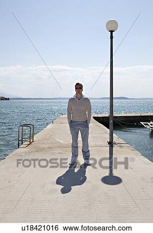 Stock Photograph - Man standing on pier by sea. Fotosearch