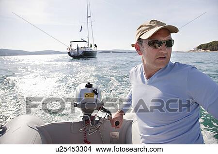 Picture - Man steering yacht dinghy. Fotosearch