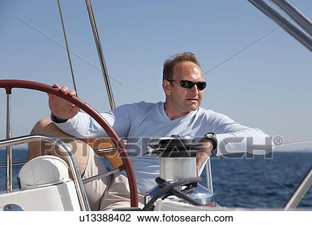 Stock Image - Man steering yacht. Fotosearch