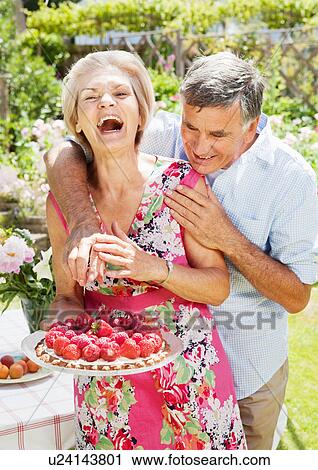 Stock Image - man tries to steal strawberry of tart.. Fotosearch