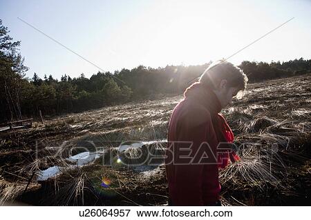 Stock Photo - Man walking through sunlit forest scene. Fotosearch