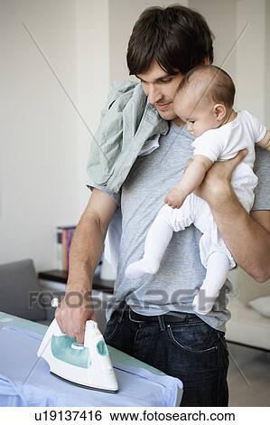 Stock Photograph - Man with baby ironing. Fotosearch