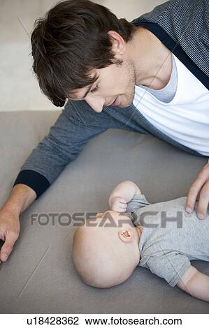 Stock Image - Man with baby on sofa. Fotosearch