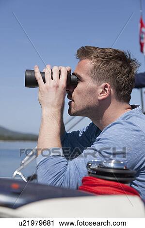 Stock Image - Man with binoculars on yacht. Fotosearch