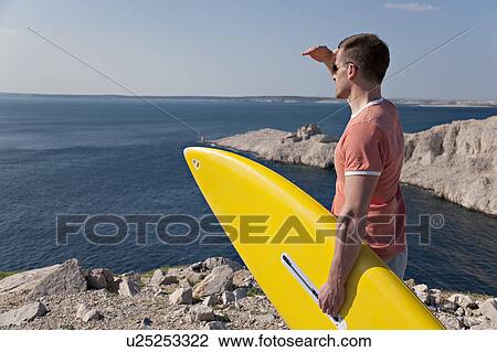 Man with surfboard looking at sea View Large Photo Image Stock Image - Man with surfboard looking at sea. Fotosearch