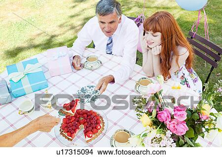 Picture - mature man is offered a piece of cake.. Fotosearch