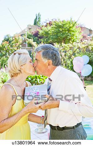 Picture - Mature man offers present to partner.. Fotosearch