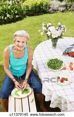Mature woman peeling pods in garden. View Large Photo Image Stock Image - Mature woman peeling pods in garden.. Fotosearch