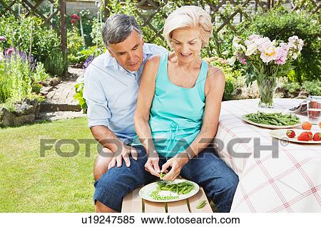 Mature woman peels pods, partner looks on View Large Photo Image Stock Photography - Mature woman peels pods, partner looks on. Fotosearch