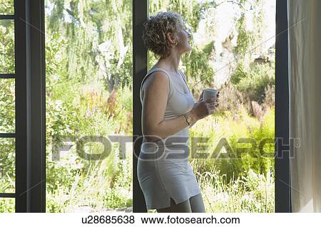 Stock Photo - Mature woman resting against door. Fotosearch