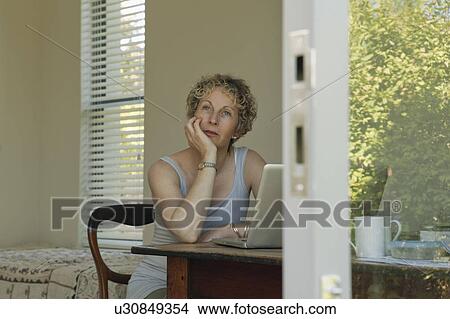Picture - Mature woman sitting at desk. Fotosearch