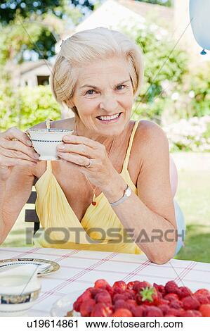 Stock Image - mature woman with cup of tea, smiling.. Fotosearch