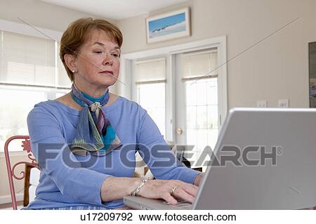 Stock Image - Mature woman working on computer. Fotosearch