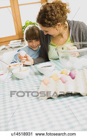 Stock Image - mother and child coloring Easter eggs. Fotosearch