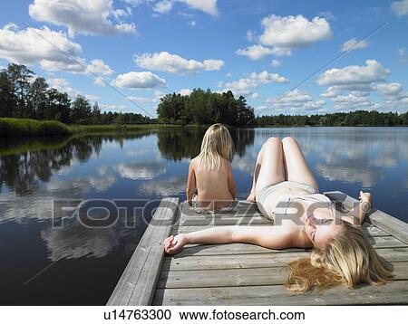 Stock Image - Mother and daughter tanning on a dock. Fotosearch