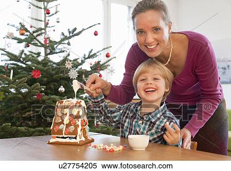 Stock Photography - mother, boy decorating gingerbread house. Fotosearch