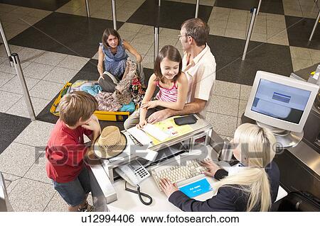 Stock Photograph - Mother checkin suitcase for vouchers. Fotosearch