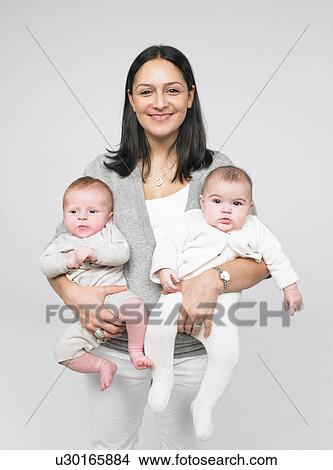 Picture - Mother holding two babies. Fotosearch