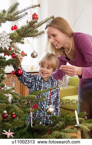 Stock Image - mother, son decorating christmas tree. Fotosearch