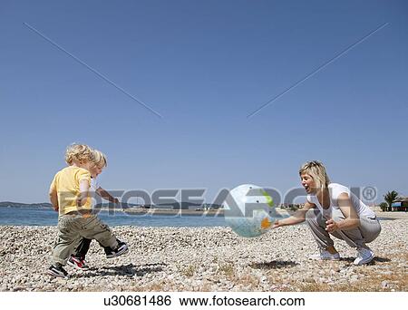 Mother with twins at beach playing ball View Large Photo Image Stock Photograph - Mother with twins at beach playing ball. Fotosearch